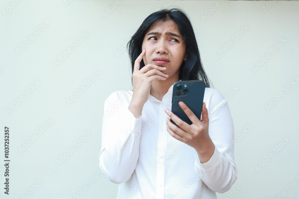 dark hair pondering asian young business woman wear white formal suit using mobile phone app looking away show worry face expression, read bad news and message, standing over isolated background dark hair pondering asian young business woman wear white formal suit using mobile phone app looking away show worry face expression, read bad news and message, standing over isolated background