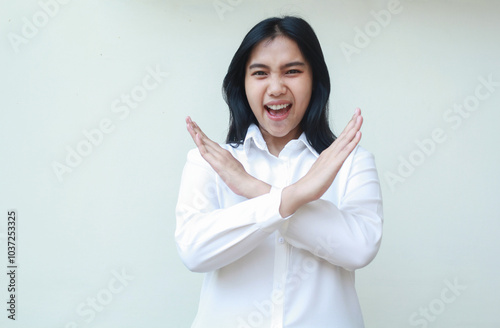 carefree excited asian young business woman cross hands over chest show stop signs, warning and forbidden gesture, screaming to camera wearing white formal shirt, standing over isolated background