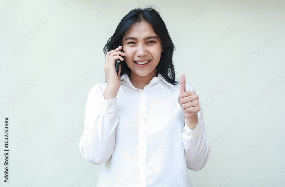 portrait of successful confident asian young woman entrepreneur speaking on smartphone and looking at camera giving thumbs up feeling satisfied of service wearing white formal shirt, standing isolated portrait of successful confident asian young woman entrepreneur speaking on smartphone and looking at camera giving thumbs up feeling satisfied of service wearing white formal shirt, standing isolated