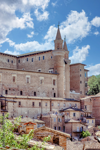A stunning view of Urbino's cityscape showcasing the impressive Palazzo Ducale under a bright blue sky. Palazzo Ducale Castle of the Dukes of Urbino, Italy