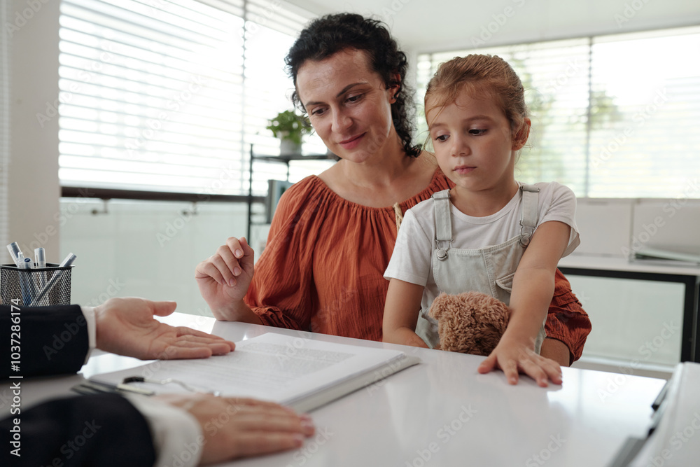 Young mother signing application while having meeting with social worker in social service