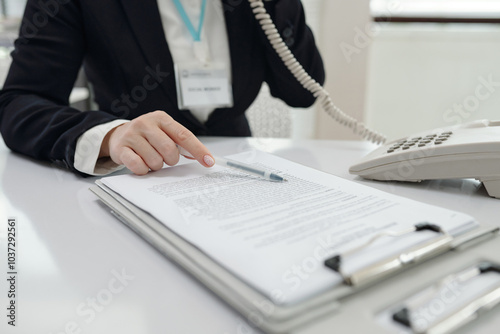 Social worker discussing document by the phone while sitting at her workplace in office photo