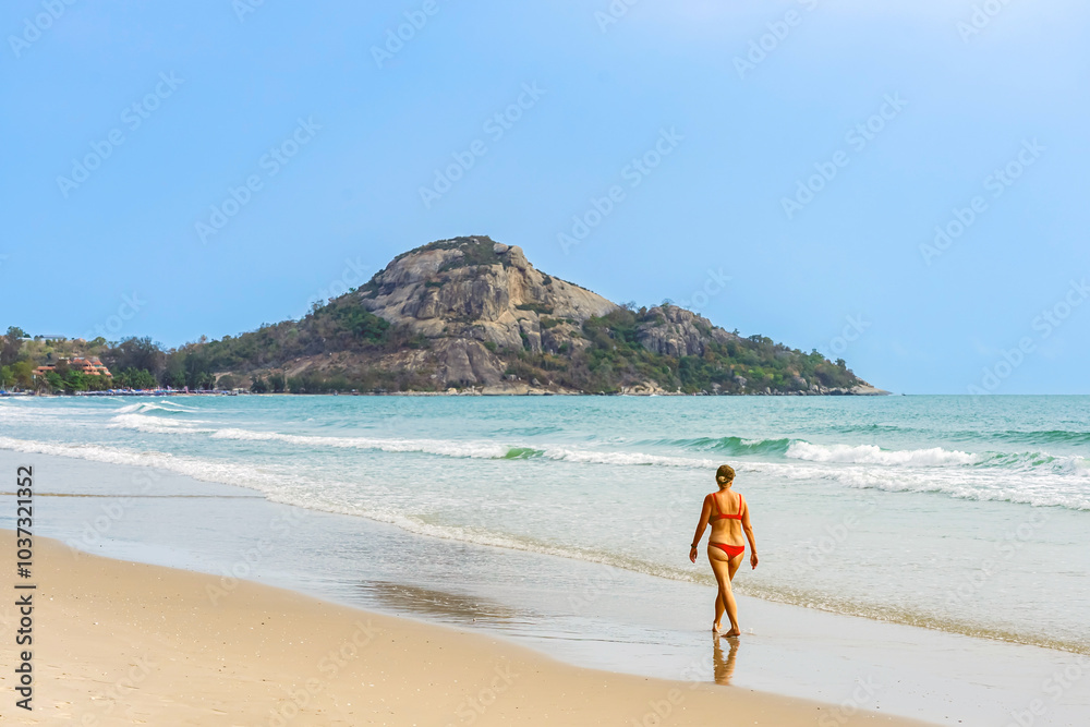 Back view of woman wear red bikini walk on beach. Happy mature woman while walking along the beach. Carefree lady walking on coastline at beach. Concept of senior lifestyle,travel,relaxing in nature. Back view of woman wear red bikini walk on beach. Happy mature woman while walking along the beach. Carefree lady walking on coastline at beach. Concept of senior lifestyle,travel,relaxing in nature.