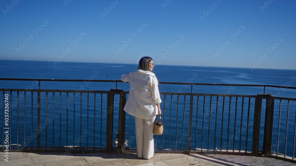 Young hispanic woman admiring the beautiful sea view in polignano a mare, puglia, italy, while standing at a scenic viewpoint. Young hispanic woman admiring the beautiful sea view in polignano a mare, puglia, italy, while standing at a scenic viewpoint.