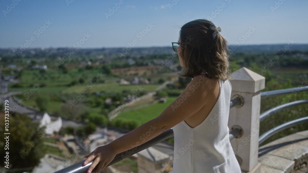 Young hispanic woman enjoying stunning viewpoint in locorotondo, puglia, italy, overlooking scenic countryside and old town streets. Young hispanic woman enjoying stunning viewpoint in locorotondo, puglia, italy, overlooking scenic countryside and old town streets.