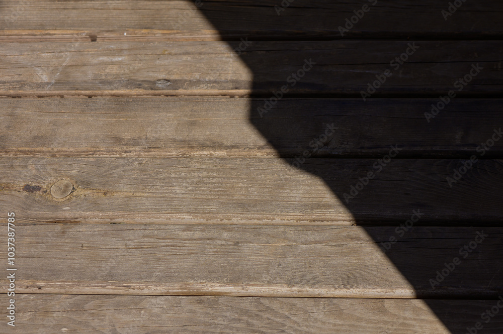 The interplay of light and shadow on weathered wooden deck boards in the afternoon sun The interplay of light and shadow on weathered wooden deck boards in the afternoon sun