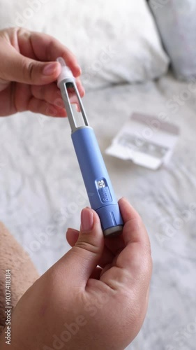 A vertical close up of a young woman priming the pen injector, prepering it for injection
