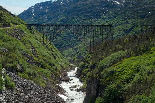 Abandoned steel bridge on Alaska's White Pass and Yukon Route Railroad, partially collapsed, crosses a rushing stream high in the mountains near Skagway.