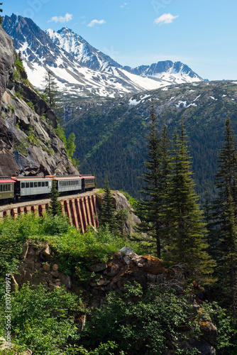 A scenic passenger train rounding a curve high in the mountains  above Skagway, Alaska