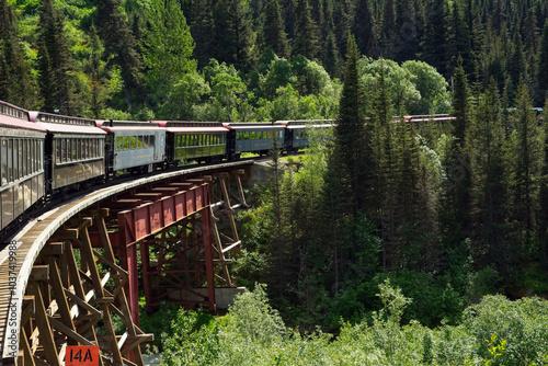 A passenger excursion train rounds a curved bridge over a ravine near Skagway, Alaska. photo