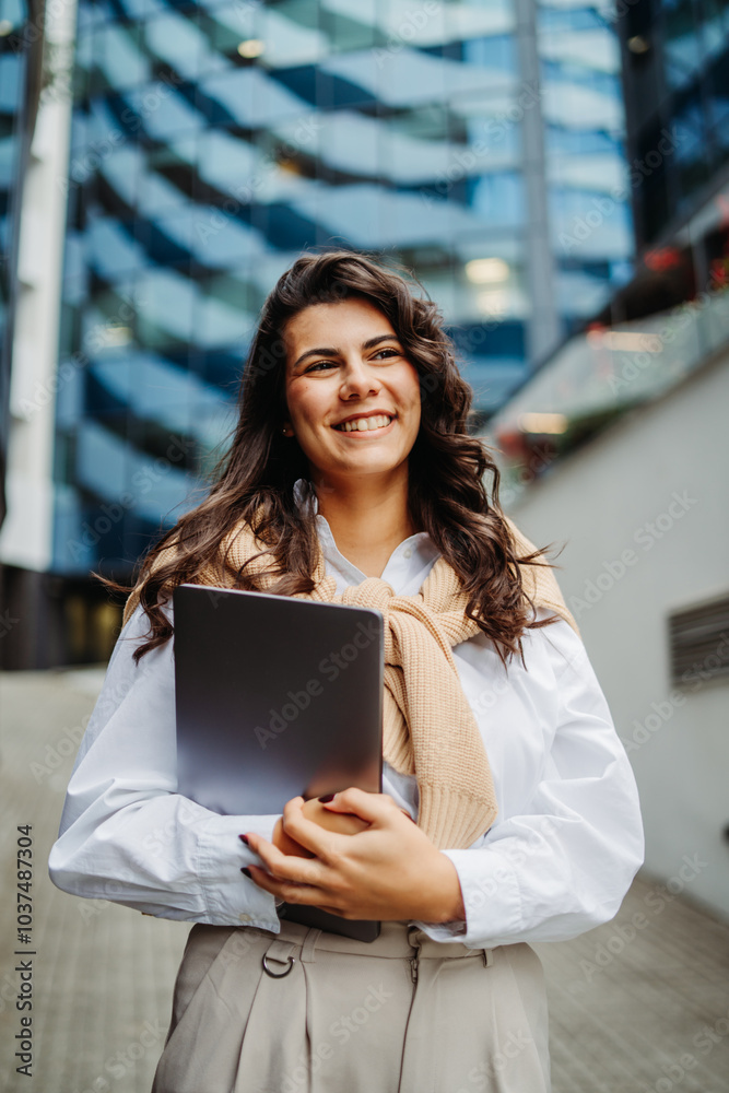 Fototapeta premium Young businesswoman going to work in front of modern business building