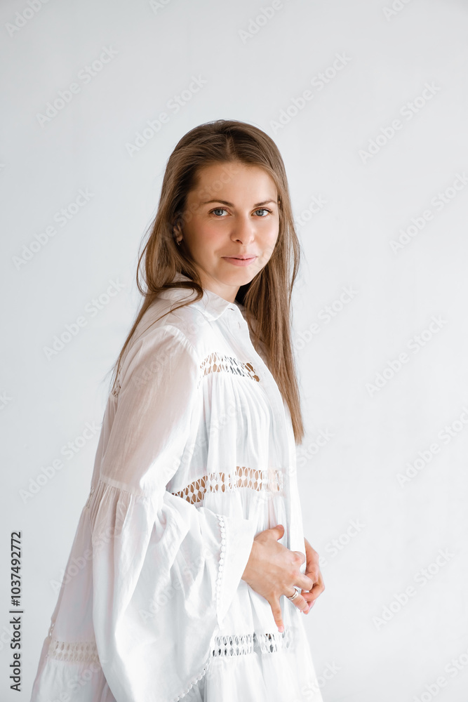 Young smiling woman wearing white top shirt looking camera isolated on grey background studio portrait. Oversize boho style dress. Posing model. Wide sleeves. Clothes for pregnant. Vertical shot Young smiling woman wearing white top shirt looking camera isolated on grey background studio portrait. Oversize boho style dress. Posing model. Wide sleeves. Clothes for pregnant. Vertical shot