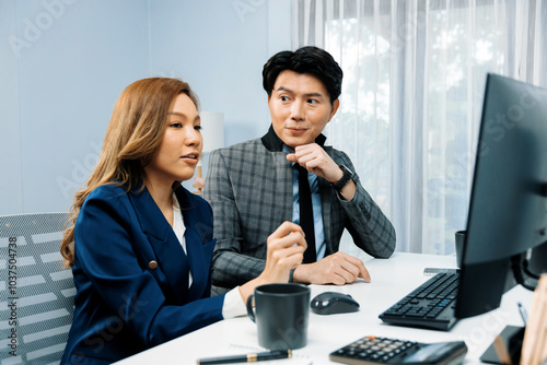 Business Asian coworkers analyzing marketing report project on two screen computer comparing value stock exchange database online report at modern office. Analyzing value investment company. Infobahn.