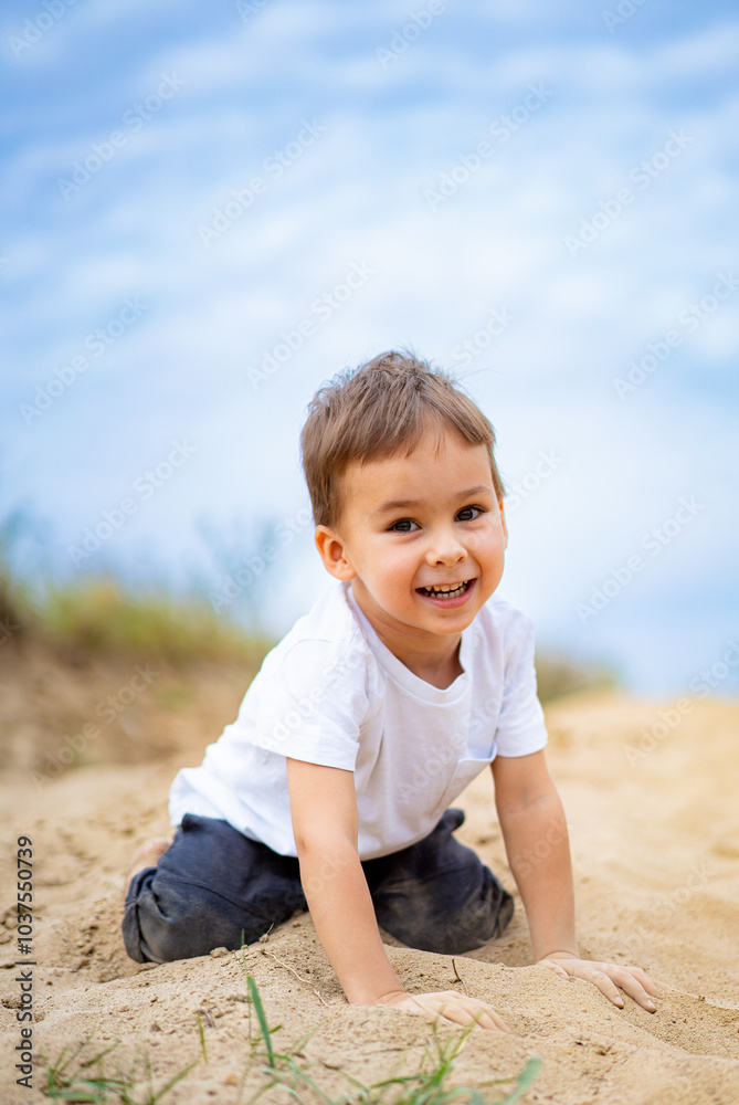 Young child playing joyfully in sand at beach. A cheerful boy is playing in the sand, enjoying a sunny day at the beach, surrounded by the calming sea and blue sky. Young child playing joyfully in sand at beach. A cheerful boy is playing in the sand, enjoying a sunny day at the beach, surrounded by the calming sea and blue sky.