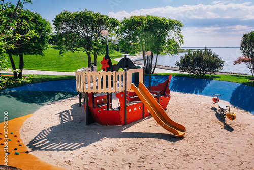 A bright playground in the form of a wooden ship, located among the lush greenery of the park for creative games for children on a sunny day.