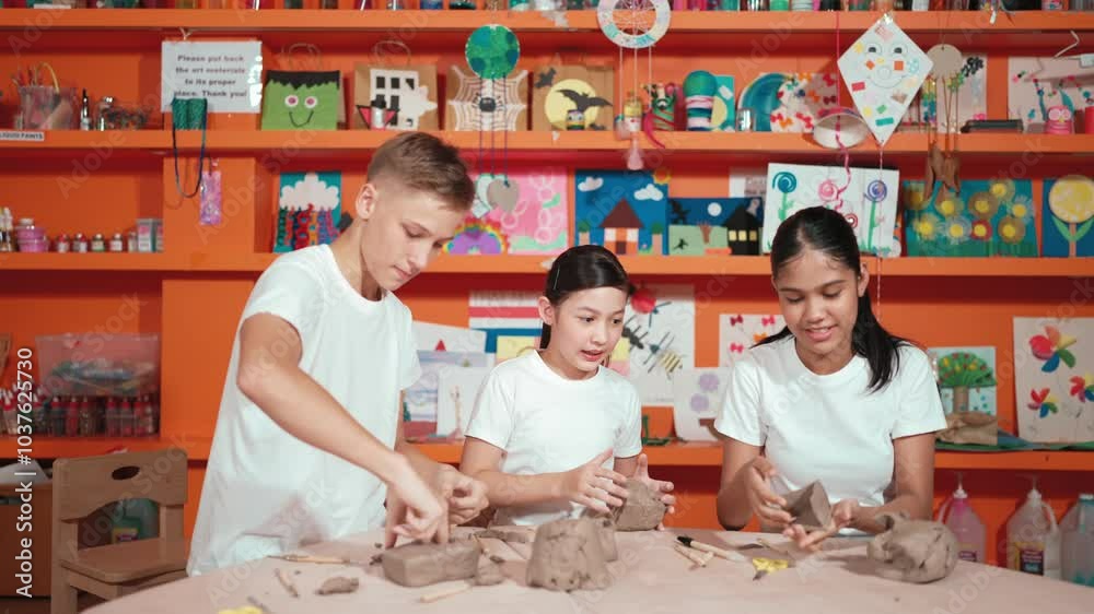 Happy diverse student modeling or working at clay in art lesson. Multicultural high school children playing dough on table while smart teenager put piece of clay as camera. Creative. Edification Happy diverse student modeling or working at clay in art lesson. Multicultural high school children playing dough on table while smart teenager put piece of clay as camera. Creative. Edification