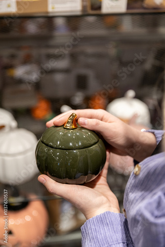 A girl chooses autumn decor for her home. Ornamental pumpkin. Ceramic pumpkin photo