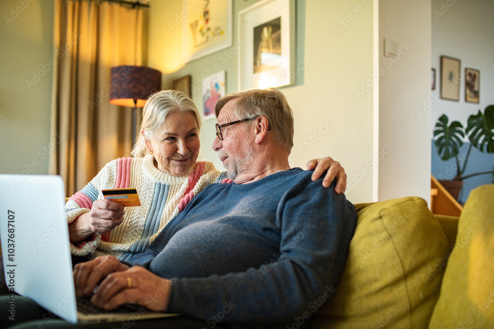 Senior couple shopping online together with credit card and laptop Senior couple shopping online together with credit card and laptop
