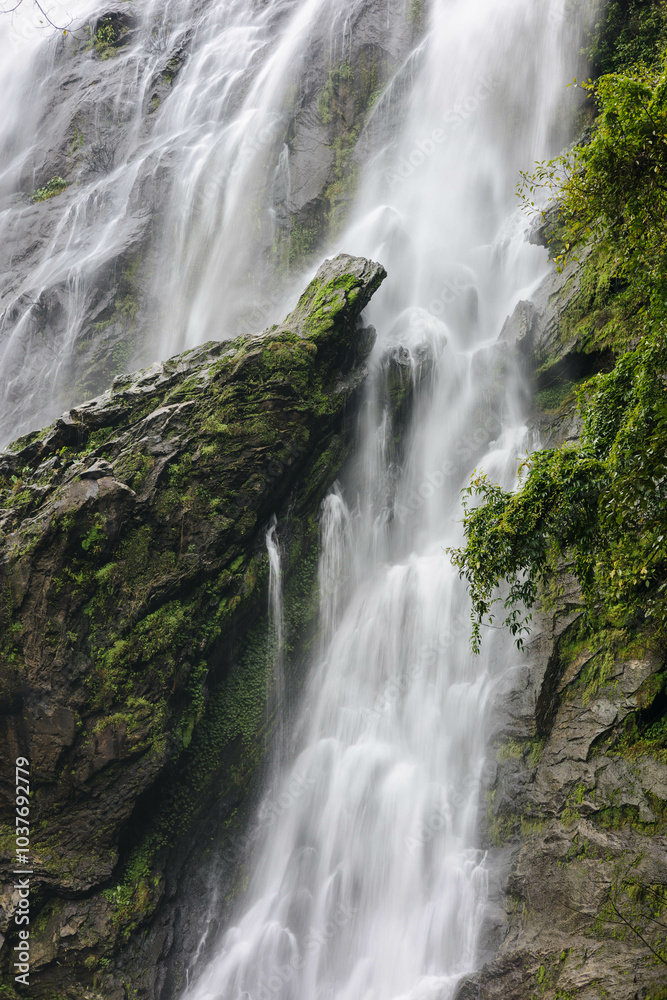 The image showcases a spectacular waterfall cascading over rugged, moss-covered rocks, surrounded by rich greenery, creating a serene yet powerful atmosphere of natural beauty. The image showcases a spectacular waterfall cascading over rugged, moss-covered rocks, surrounded by rich greenery, creating a serene yet powerful atmosphere of natural beauty.