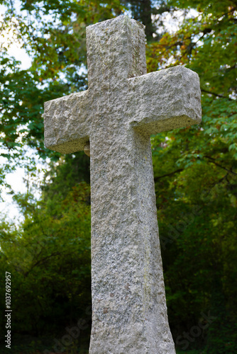 An image of a tall stone cross as a grave marker in an ancient cemetery plot. 