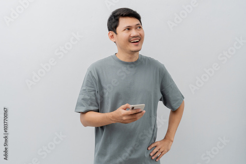 Happy expression of adult Asian man using mobile phone with casual t-shirt isolated on white background
