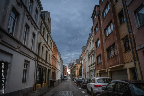 Selective blur on Residential street in Cologne city center with a mix of modern & older apartment buildings, parked cars, and overcast sky creating a quiet urban atmosphere in Nippes district, german