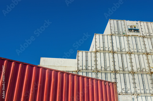 Tall wall of white refrigerated cargo containers against clear blue sky