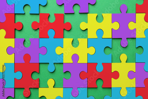 Many colorful puzzle pieces on green background, top view. Symbol of autism