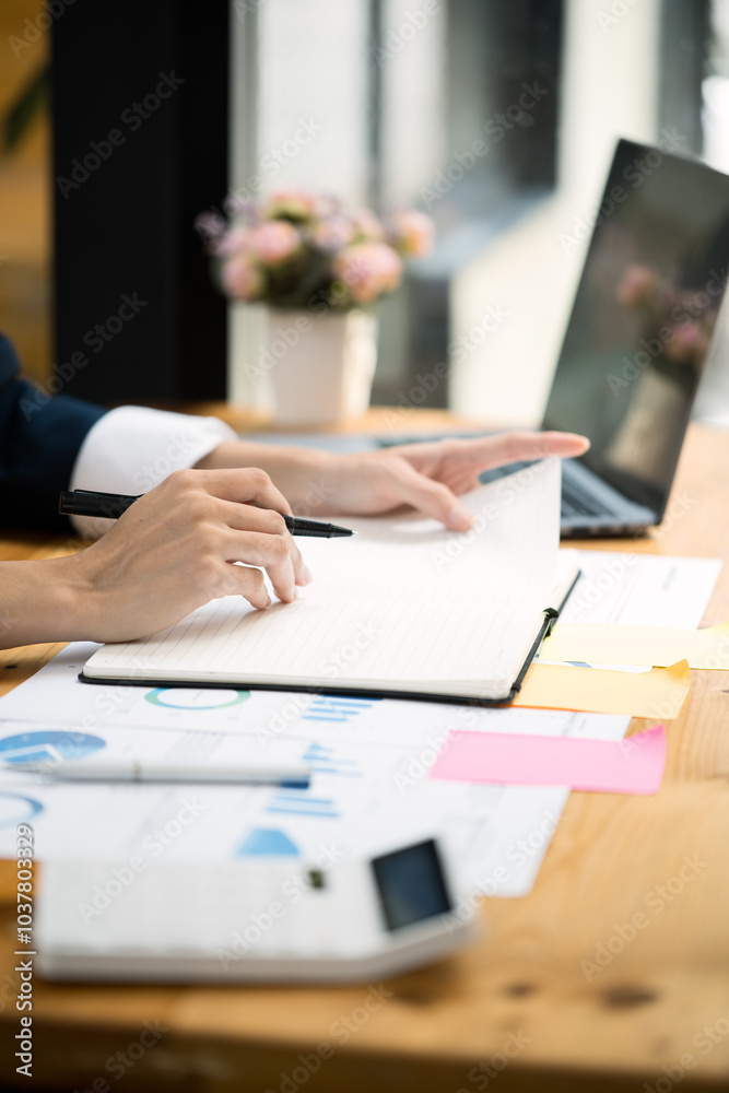 Close up of hands typing on laptop keyboard and working on document paperwork and calculator for cost financial marketing Close up of hands typing on laptop keyboard and working on document paperwork and calculator for cost financial marketing