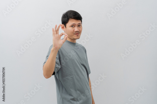 Happy expression of adult Asian man doing OK sign with casual t-shirt isolated on white background photo