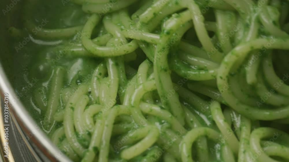 Extreme close-up view of stirring pasta with green spinach sauce in pan during cooking Extreme close-up view of stirring pasta with green spinach sauce in pan during cooking