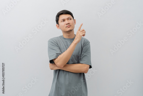 Sad and disappointed expression of adult Asian man pointing fingers with casual t-shirt isolated on white background photo