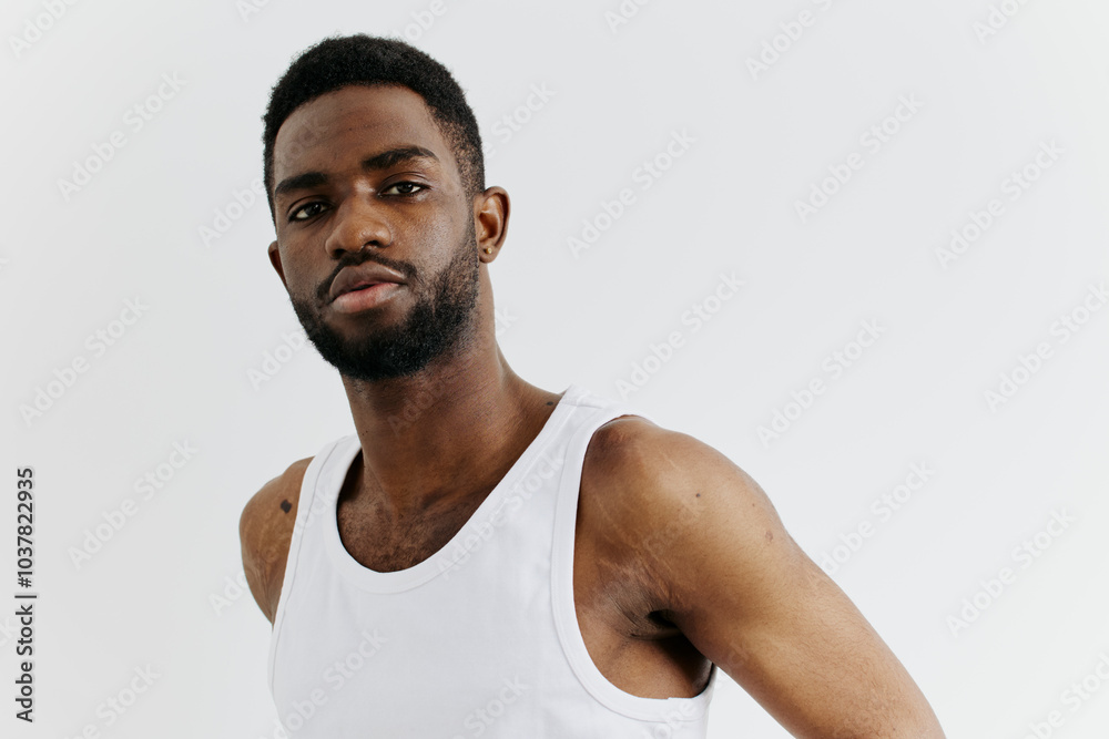 Confident african american man in white tank top standing against minimalist white background Confident african american man in white tank top standing against minimalist white background