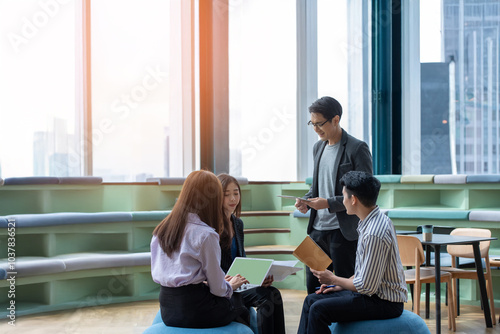 A group of Gen Z Asian business consulting, exchanging information in offices, co-working spaces.