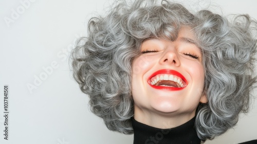 A playful moment as the woman tosses her curly silver and gray hair back while laughing, capturing her carefree attitude with a clean white background.