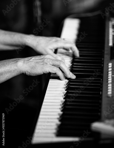 Hands playing a keyboard in high contrast black and white.