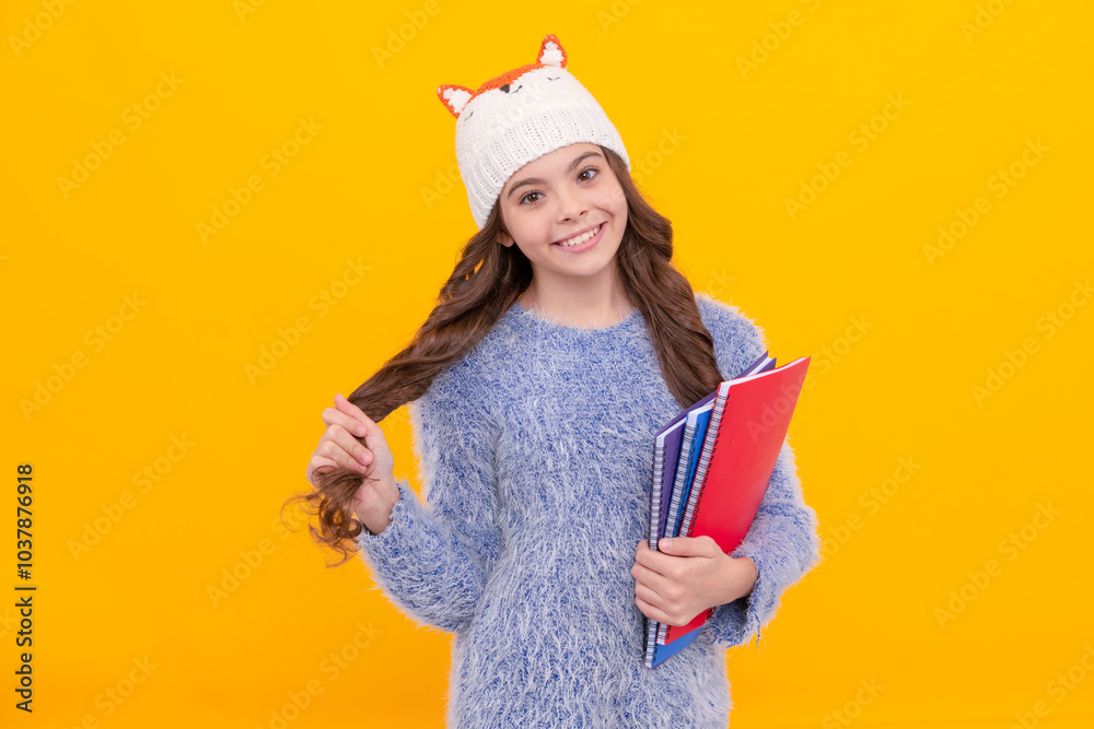 happy child in sweater and hat hold workbook on yellow background, homework happy child in sweater and hat hold workbook on yellow background, homework