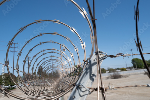 Barbed wire on the fence. Barbed wire fence delimiting the border of safe area. Security, protection, and boundaries. Barbed wire hedgehog and electric fence. Territory protection wire. photo