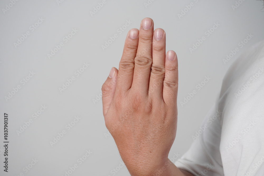 Male person shows back side of his palm, closed fingers, over grey Male person shows back side of his palm, closed fingers, over grey