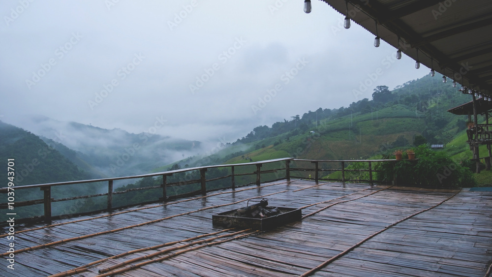 Obraz premium Landscape image of mountain view and fog from wooden balcony with bonfire on raining day