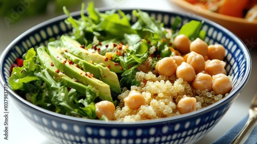 A colorful bowl of quinoa salad with avocado, chickpeas, and leafy greens, placed on a clean white background. Fresh and nutritious.