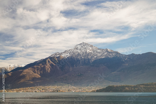 Snow caped mountain and a village against white cloud on a blue sky photo