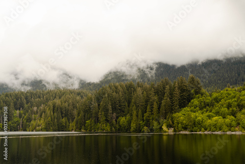 Front view of mountain in a cloud with pine trees and a lake