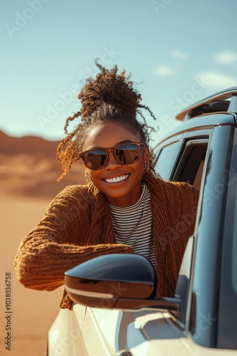 A woman enjoying a sunny day while leaning out of a car window in the desert ...