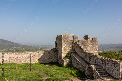 Ruins of Berat Castle perched atop hill overlooking picturesque valley in Albania. Weathered stone walls partially collapsed creating sense of history and decay. Historical significance Byzantine era photo