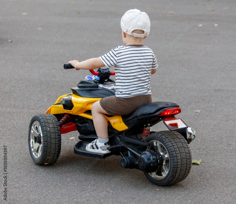 A young boy is riding a toy motorcycle A young boy is riding a toy motorcycle