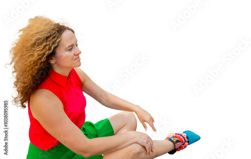 Obraz na płótnie Fashionable woman in bright clothes, with long blond curly hair, is sitting in the lotus position on the street basking in the sun and resting against the background of a modern business center. w salonie