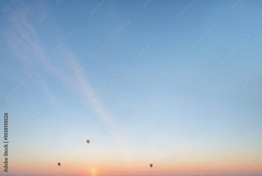 Brightly colored balloons float in the sky at sunset