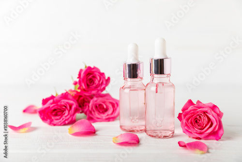 Rose essential oil on a textured background.Roses and a bottle of rose perfumed water.Aromatherapy treatment. Beauty concept. Spa procedure.Natural organic oil.Anti-stress,detox relax.Place for text