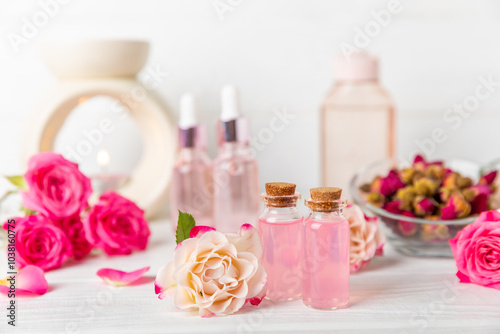 Rose essential oil on a textured background.Roses and a bottle of rose perfumed water.Aromatherapy treatment. Beauty concept. Spa procedure.Natural organic oil.Anti-stress,detox relax.Place for text